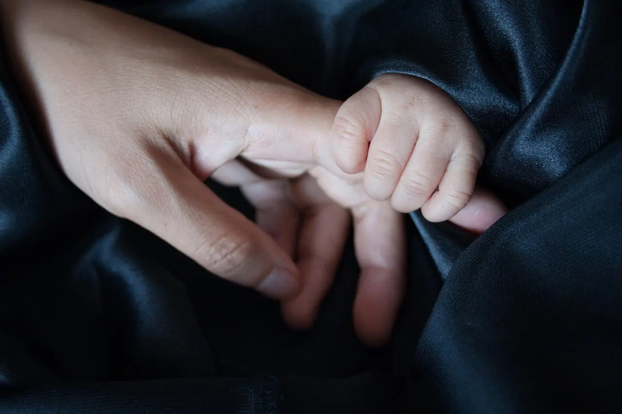 Close-up of a baby's hand gently holding an adult's finger, symbolizing love and celebrating parents