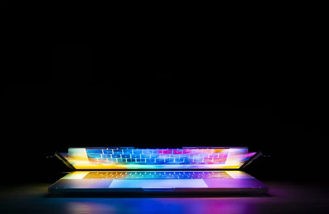Laptop glowing with colorful rainbow light from its screen and keyboard, symbolizing creativity and imagination