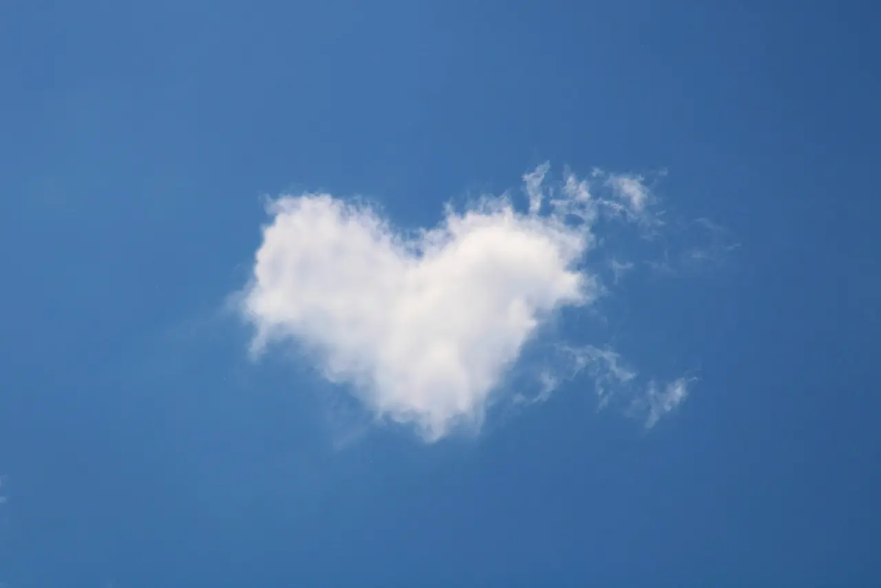 Blue sky with a fluffy white cloud shaped like a heart, symbolizing care and well wishes